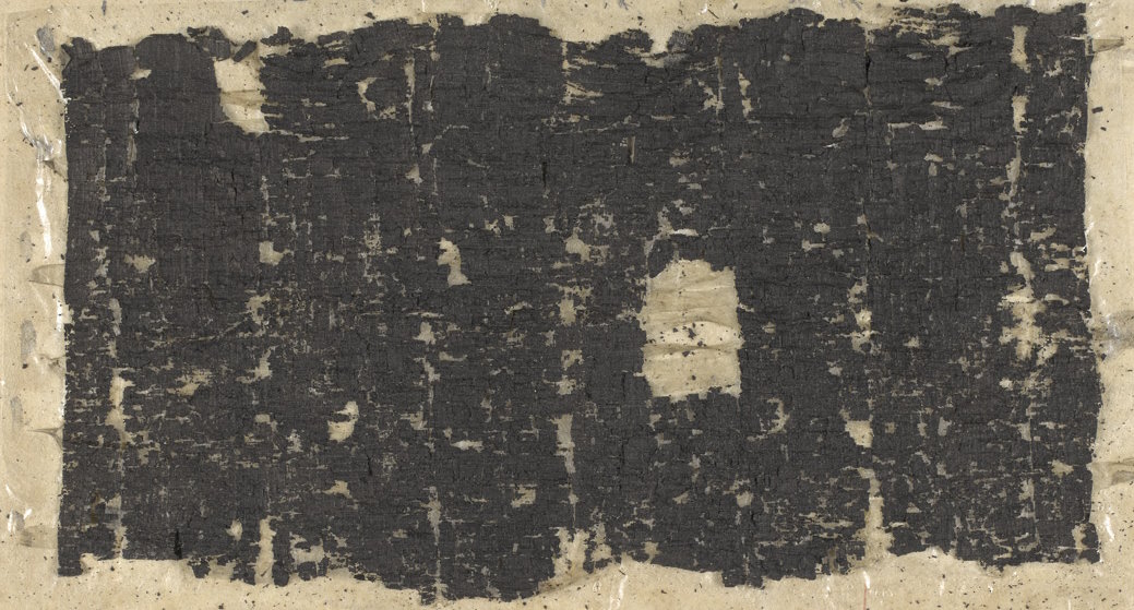 Full image of Blackened fragments of an unrolled papyrus.