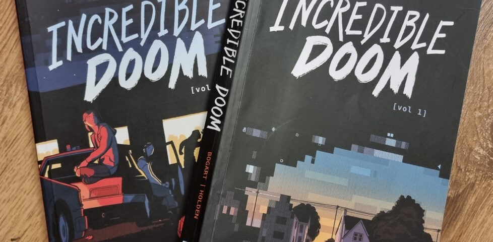 Softcover bound copies of volumes 1 and 2 of Incredible Doom, on a wooden surface.
