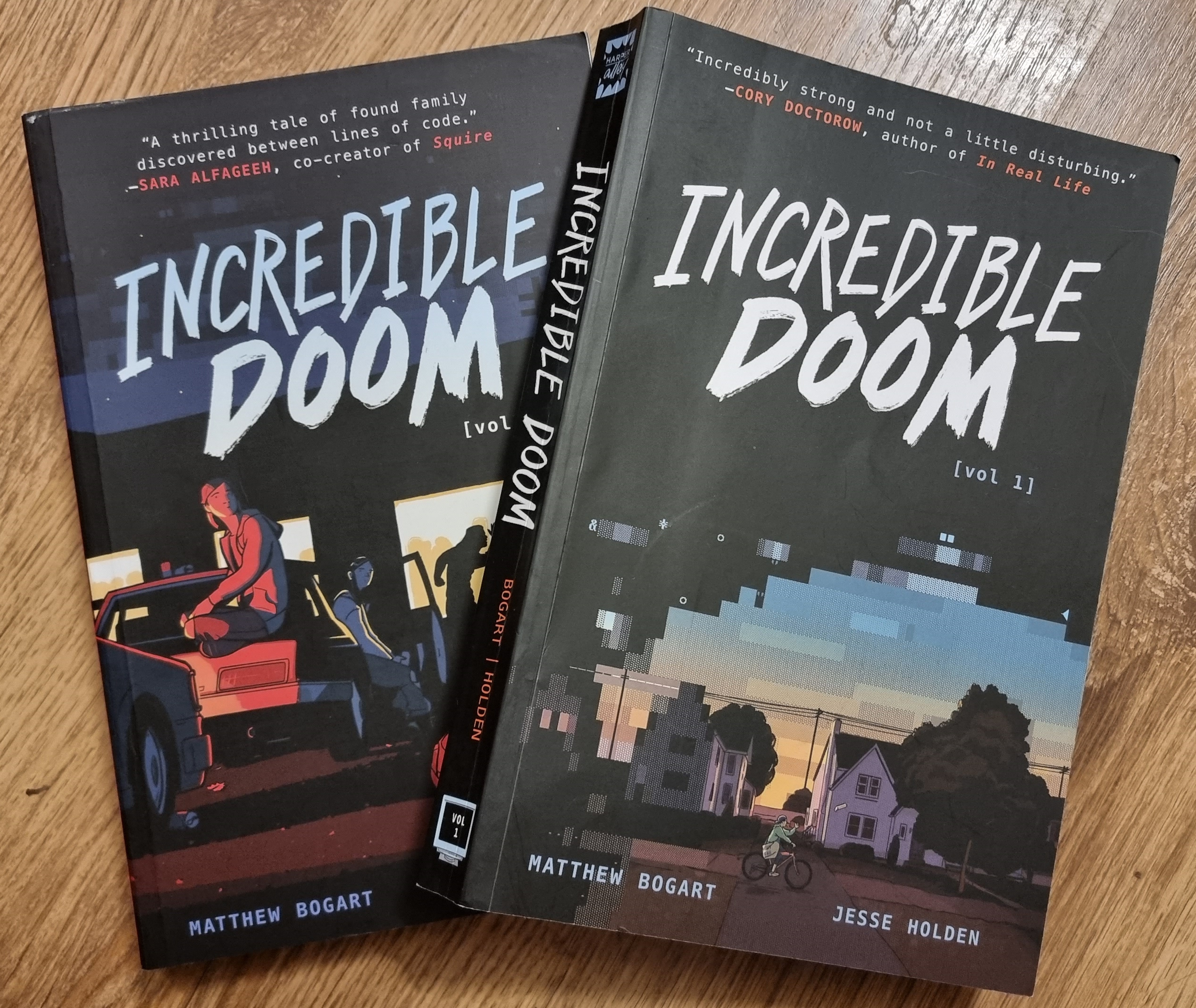 Full image of Softcover bound copies of volumes 1 and 2 of Incredible Doom, on a wooden surface.