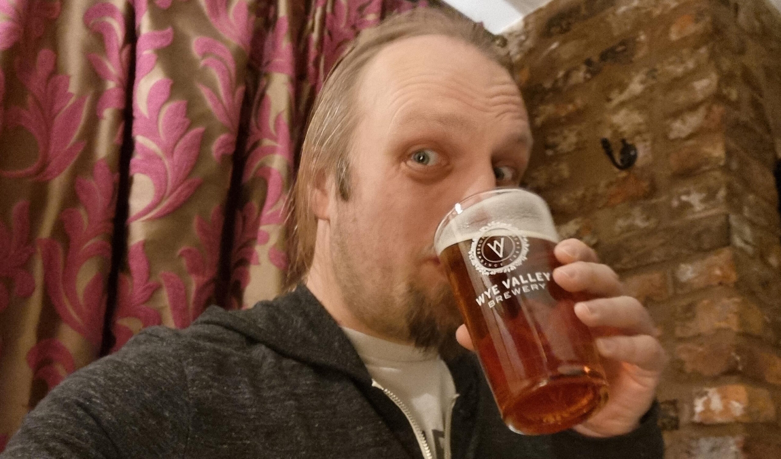 Full image of Dan drinking beer from a Wye Valley Brewery pint glass.