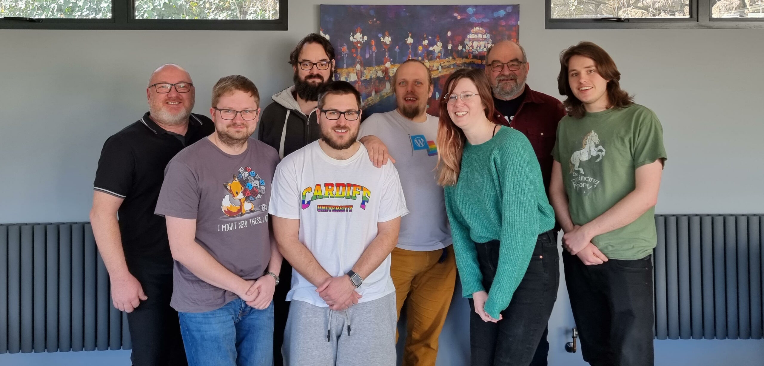 Full image of Dan poses in the centre of a group of seven other Three Rings volunteers.