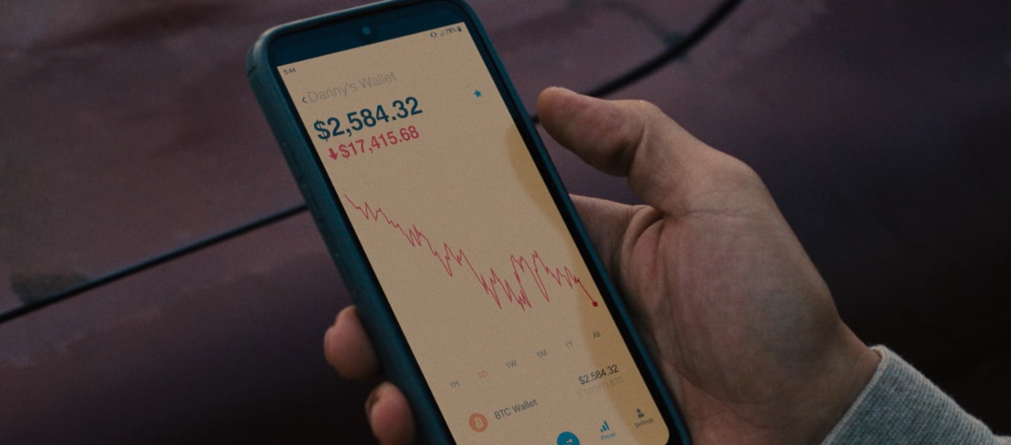 Full image of Screengrab from BEEF Series 1, Episode 1, showing a held mobile phone showing a Bitcoin wallet's value crashing by 87%