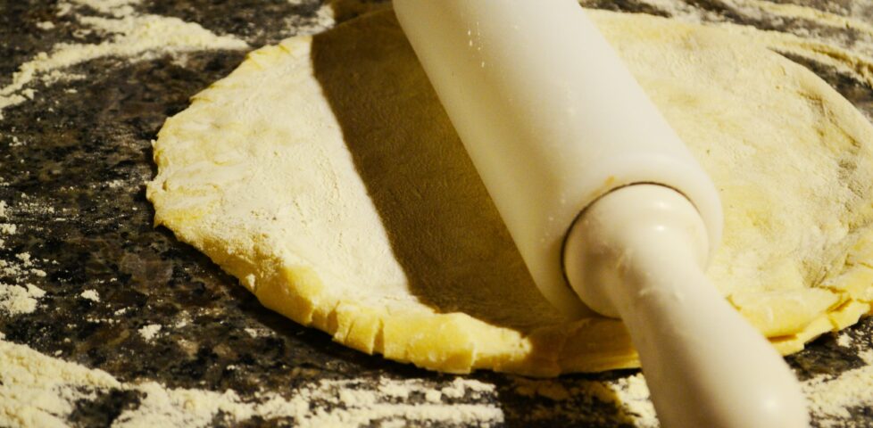 A circle of pizza dough on a worktop, a rolling pin atop it.