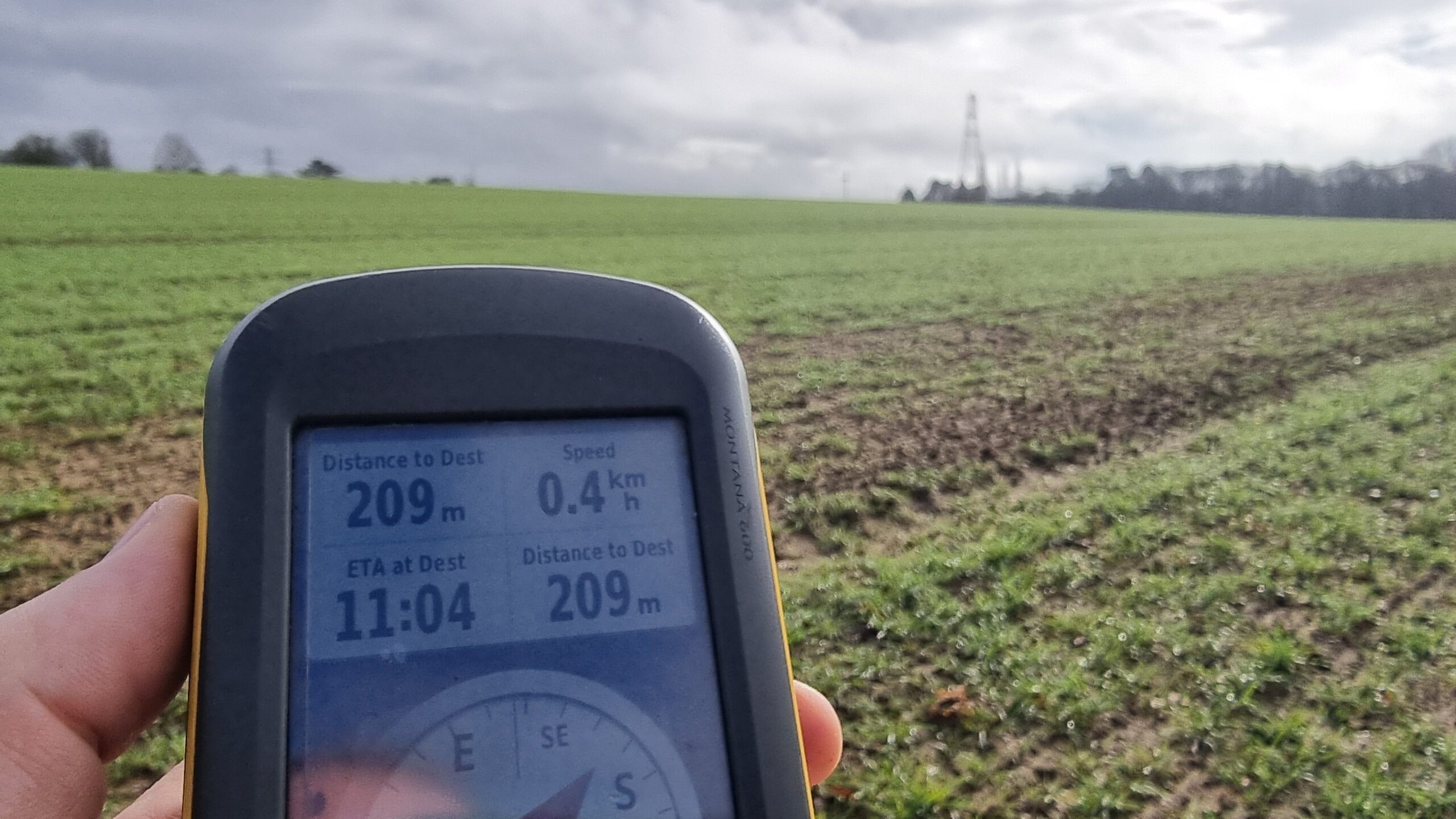 Full image of GPSr, held up in a fallow field, reading 209m from destination.
