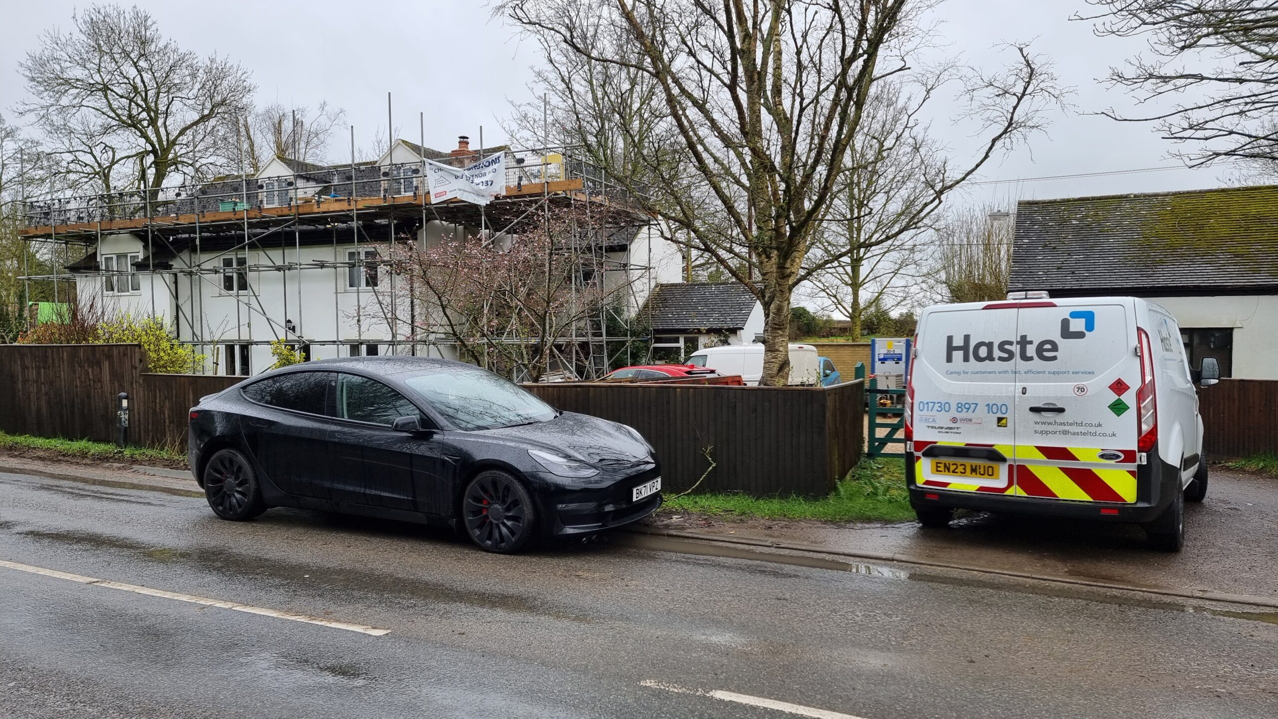 Full image of A driveway full of vehicles spills out onto the nearby road.