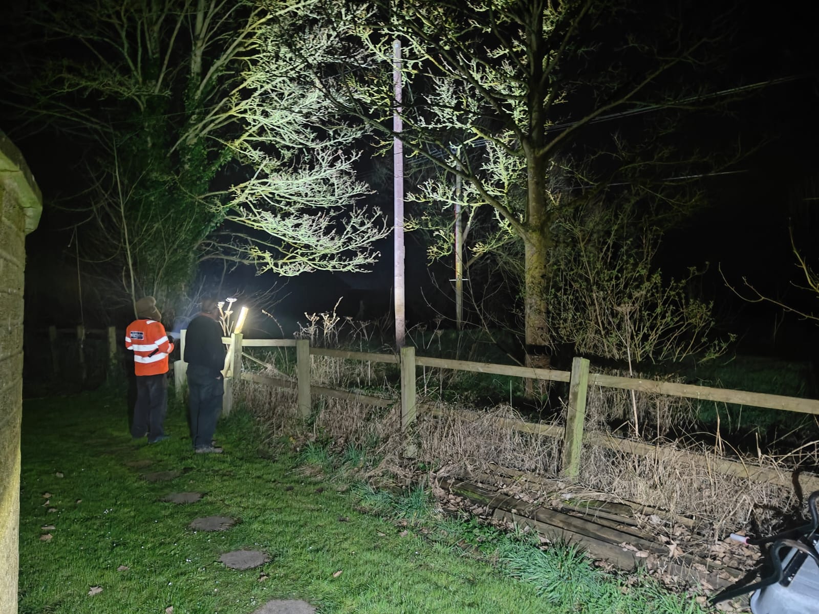 Full image of Linesmen examining an electricity pylon by torchlight.