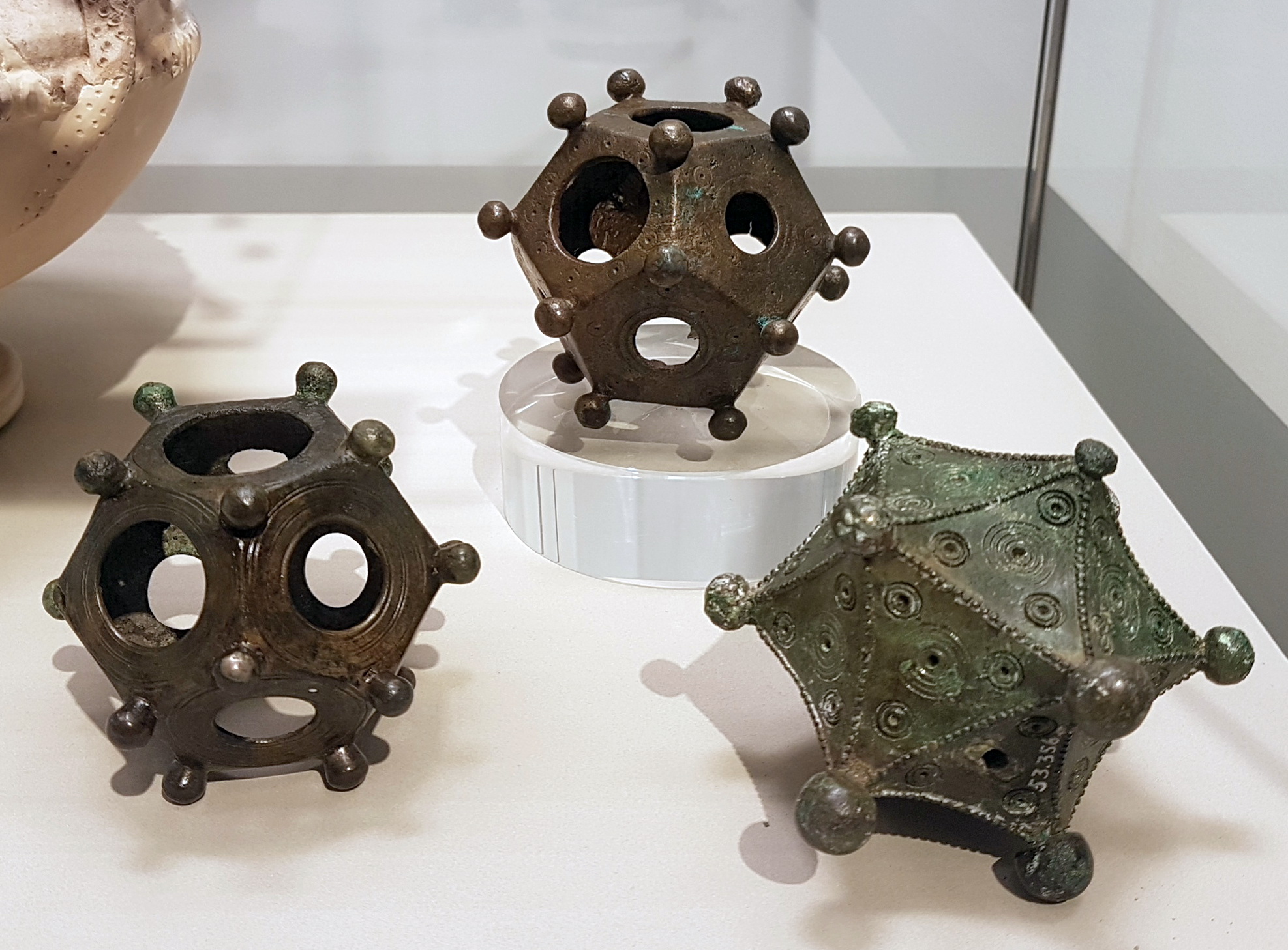 Full image of Two ancient Roman bronze dodecahedrons and an icosahedron (3rd c. AD) in the Rheinisches Landesmuseum in Bonn, Germany. The dodecahedrons were excavated in Bonn and Frechen-Bachem; the icosahedron in Arloff. Photo courtesy Kleon3 on Wikipedia, used under a Creative Commons license.
