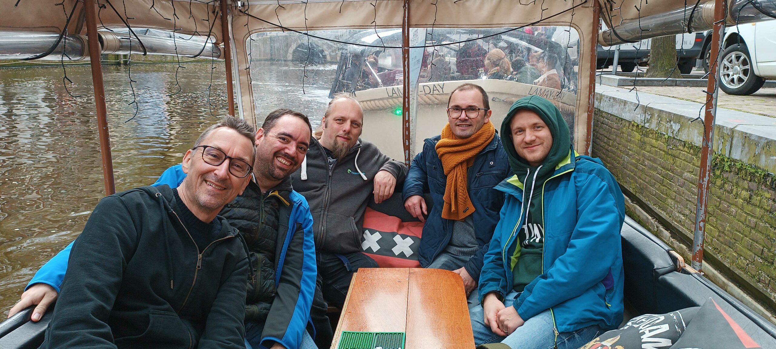 Full image of Dan, with four other men, sit in the back of a covered boat on a canal.