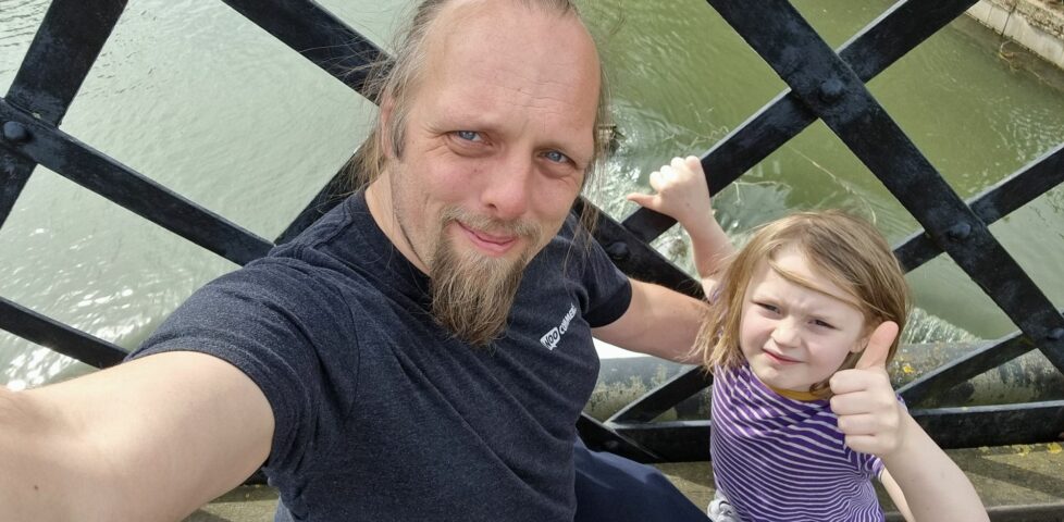 Dan sits on an iron bridge with a 7-year-old boy, above a raging weir.