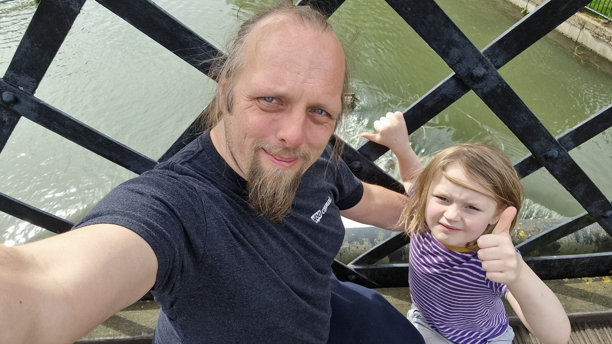 Full image of Dan sits on an iron bridge with a 7-year-old boy, above a raging weir.
