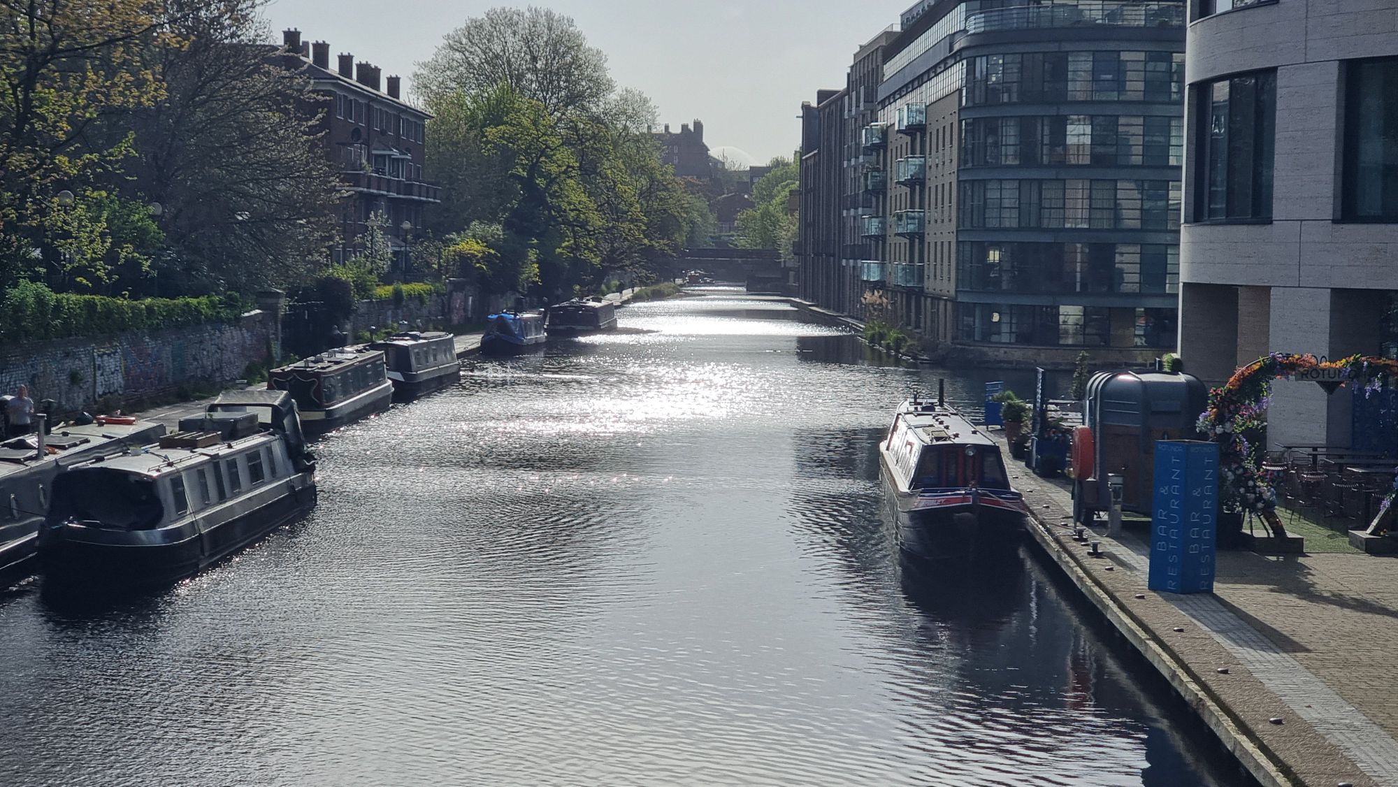 Full image of Early morning sun reflects in the water of a peaceful wide canal in central London.