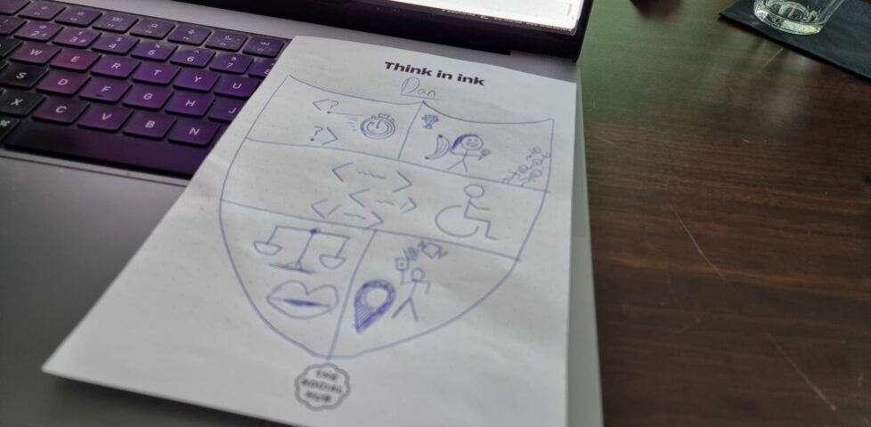 Hand-sketched personal coat of arms on notepaper, atop a laptop keyboard.
