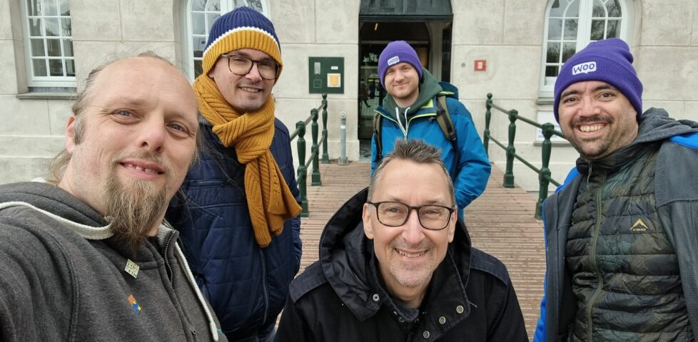 Five men in thick coats stand at the entrance to a museum.