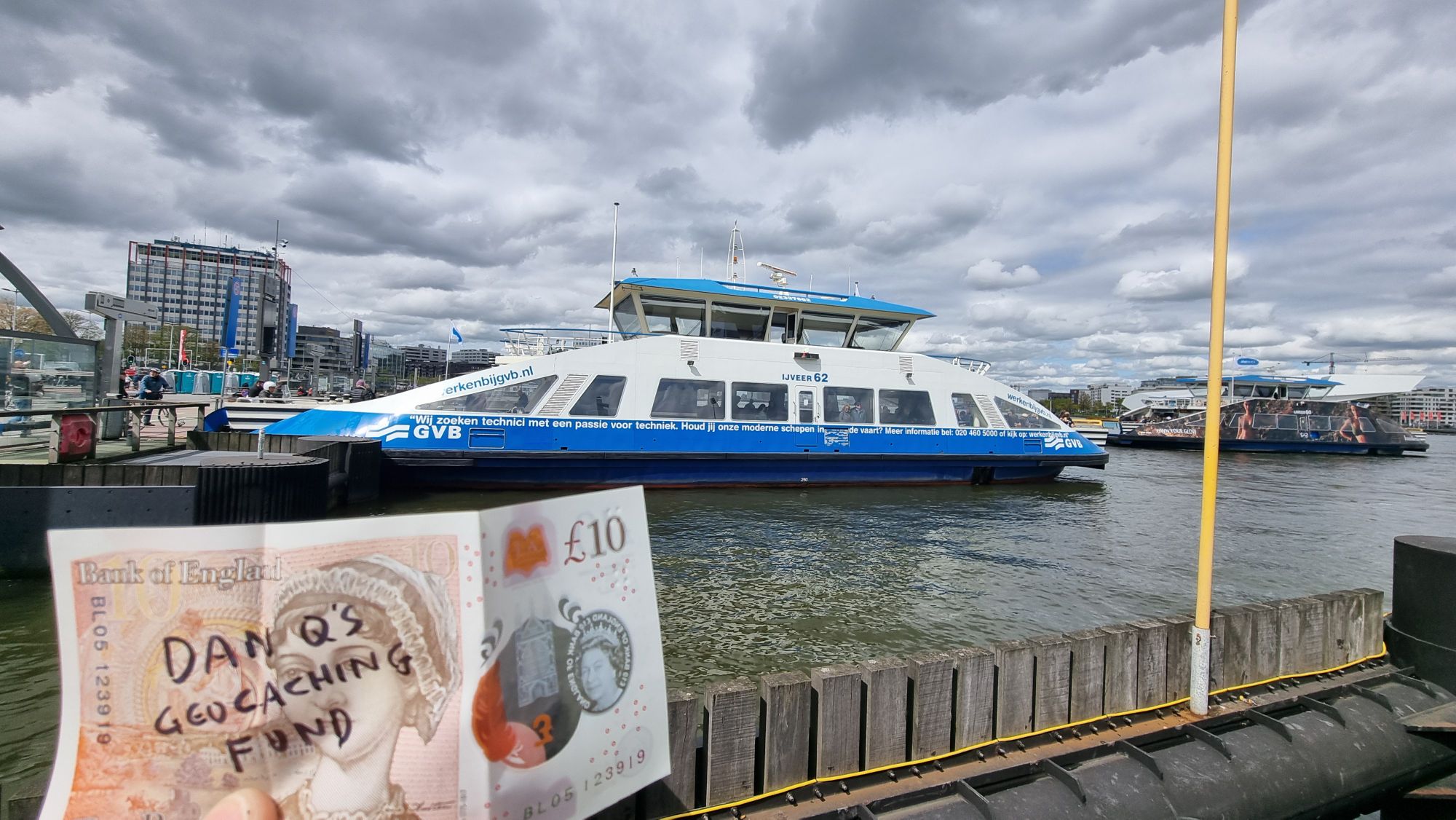 Full image of A £10 note with "Dan Q's Geocaching Fund" written on it in front of a ferry.