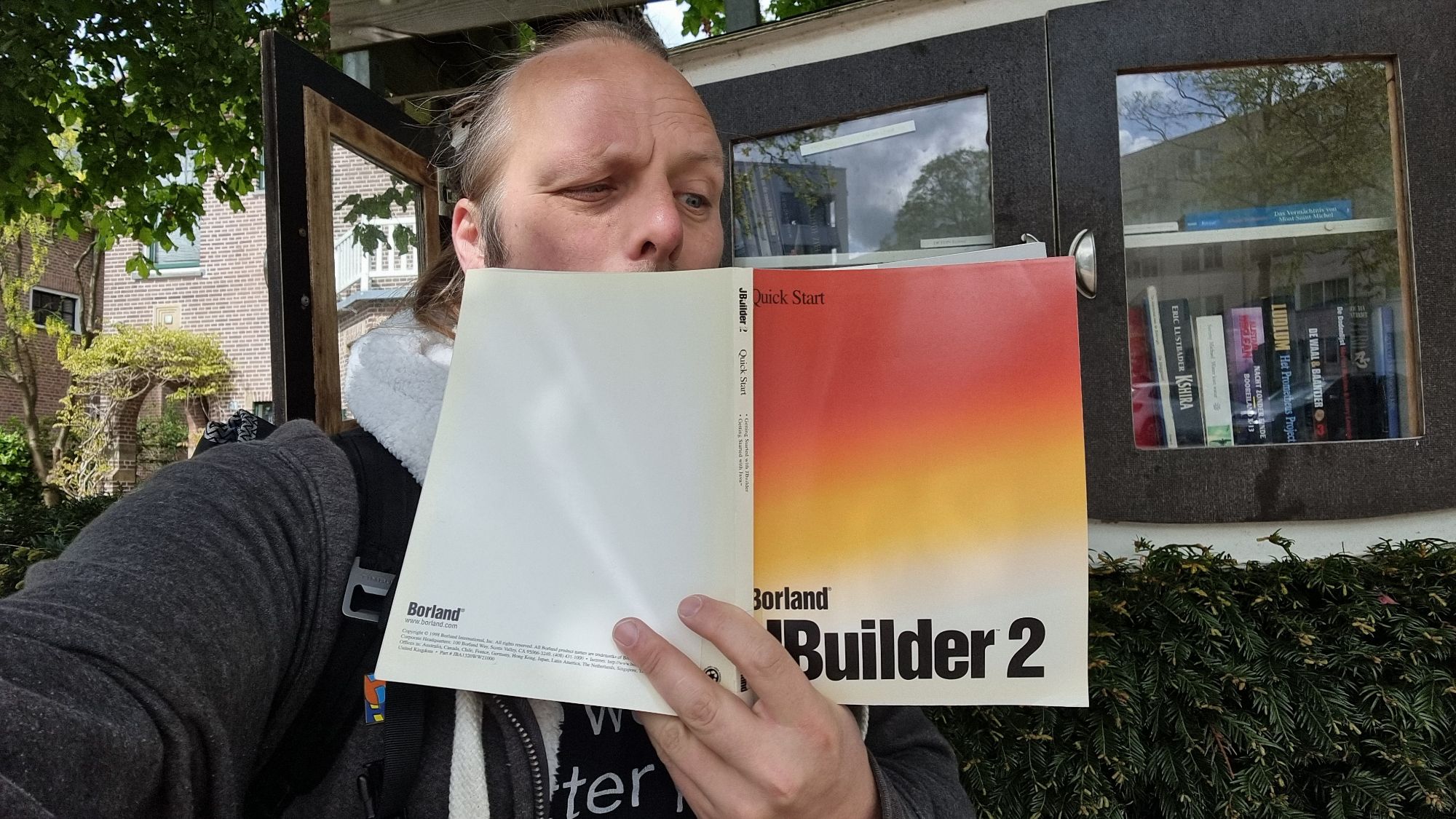 Full image of Dan squints into a copy of a book, Borland JBuilder 2 Quick Start.
