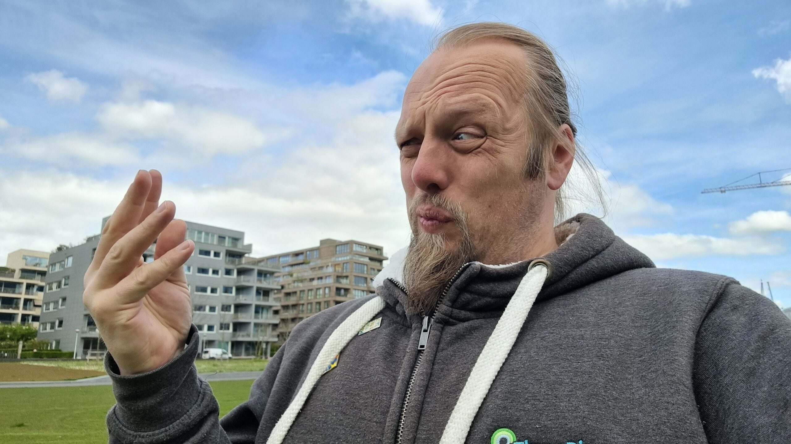 Full image of Dan looks at his fingers as if there's something disgusing on them, in a field.