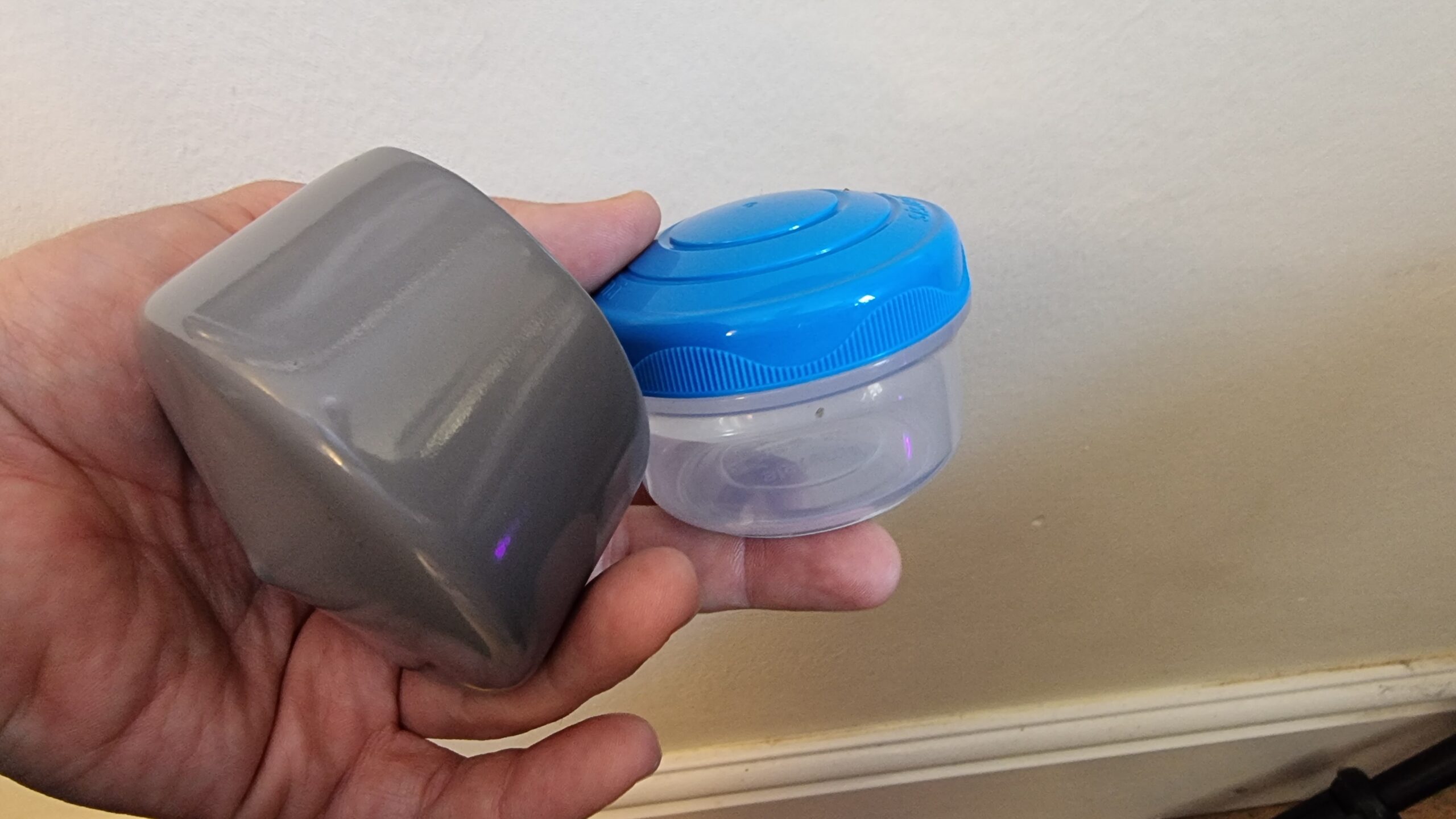 Full image of A small plastic screw-top tub and post topper; components for the geocache.