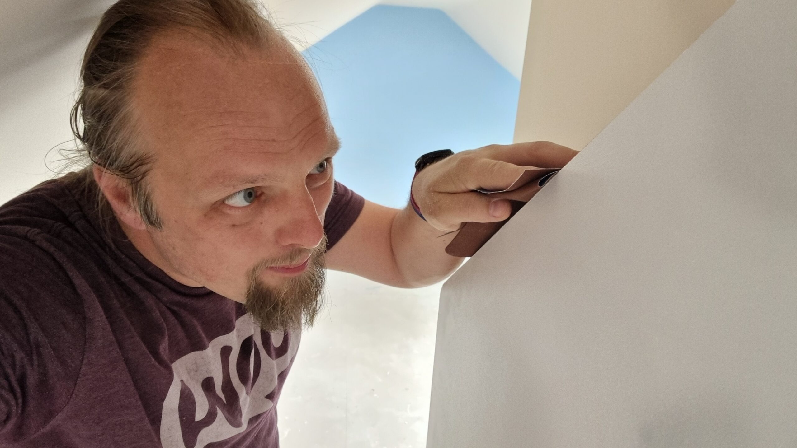 Full image of Dan rubs sandpaper atop a wooden door.