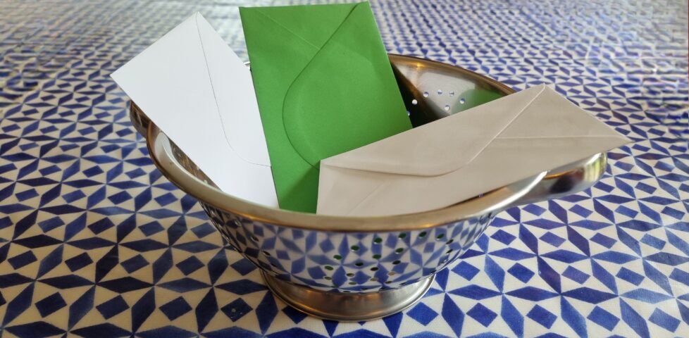 A colander containing three envelopes.