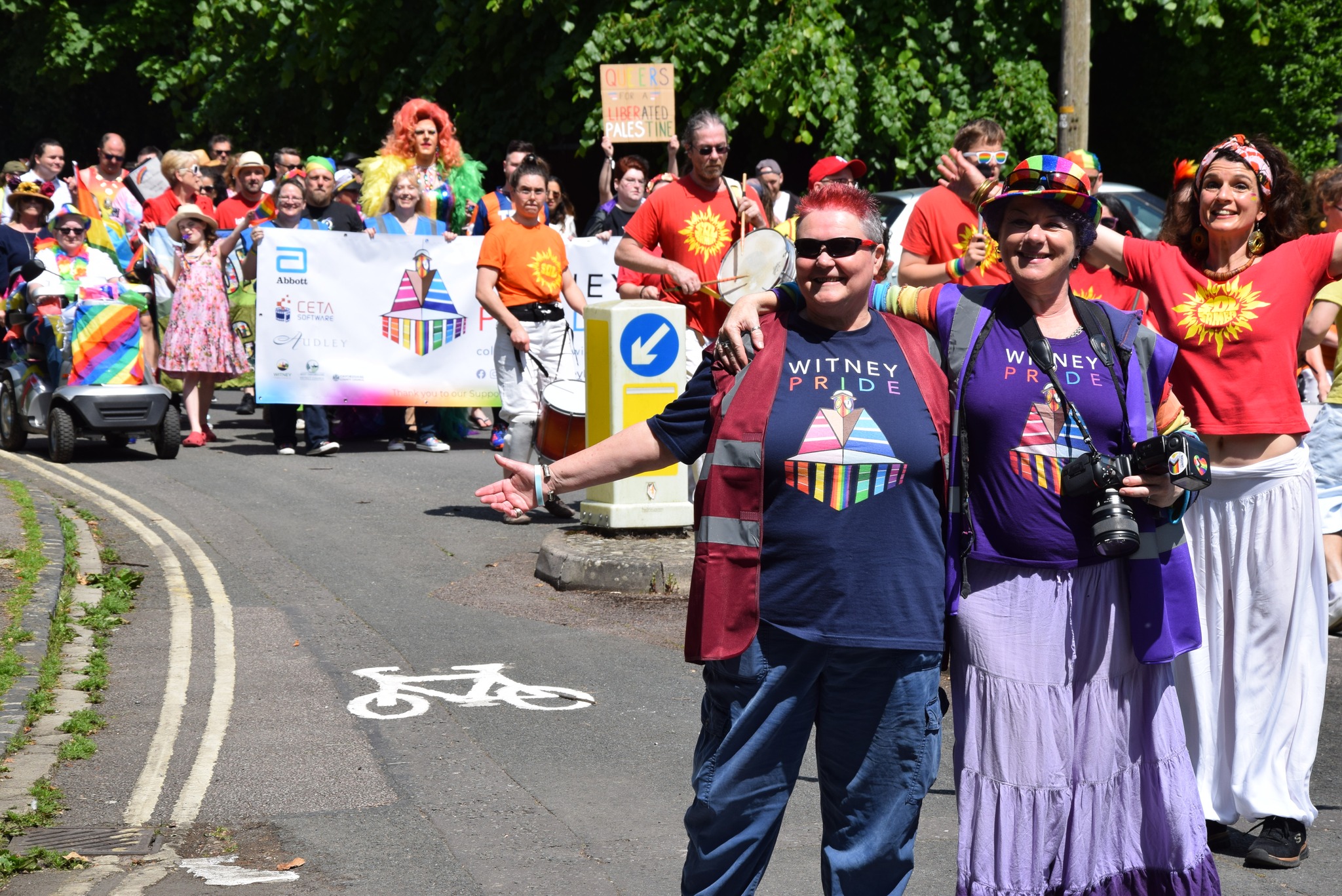 Full image of A Pride parade marches down a high street: Dan and his eldest can be seen in the very background.