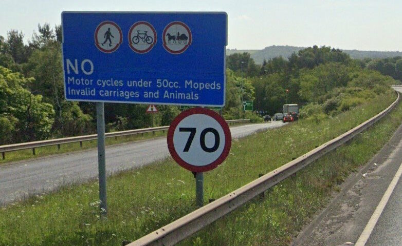 Google Street View photo from the A1 East of Edinburgh, showing a blue "No motor cycles under 50cc, moped,s invalid carriages and animals" sign alongside a 70mph sign.