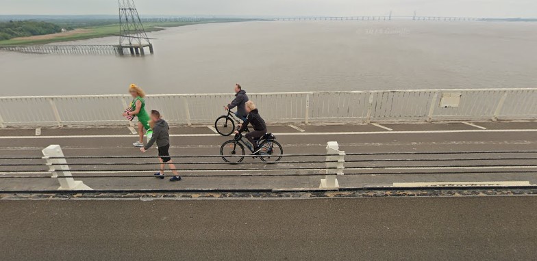 Full image of Cyclists alongside a 'motorway' river bridge lane.