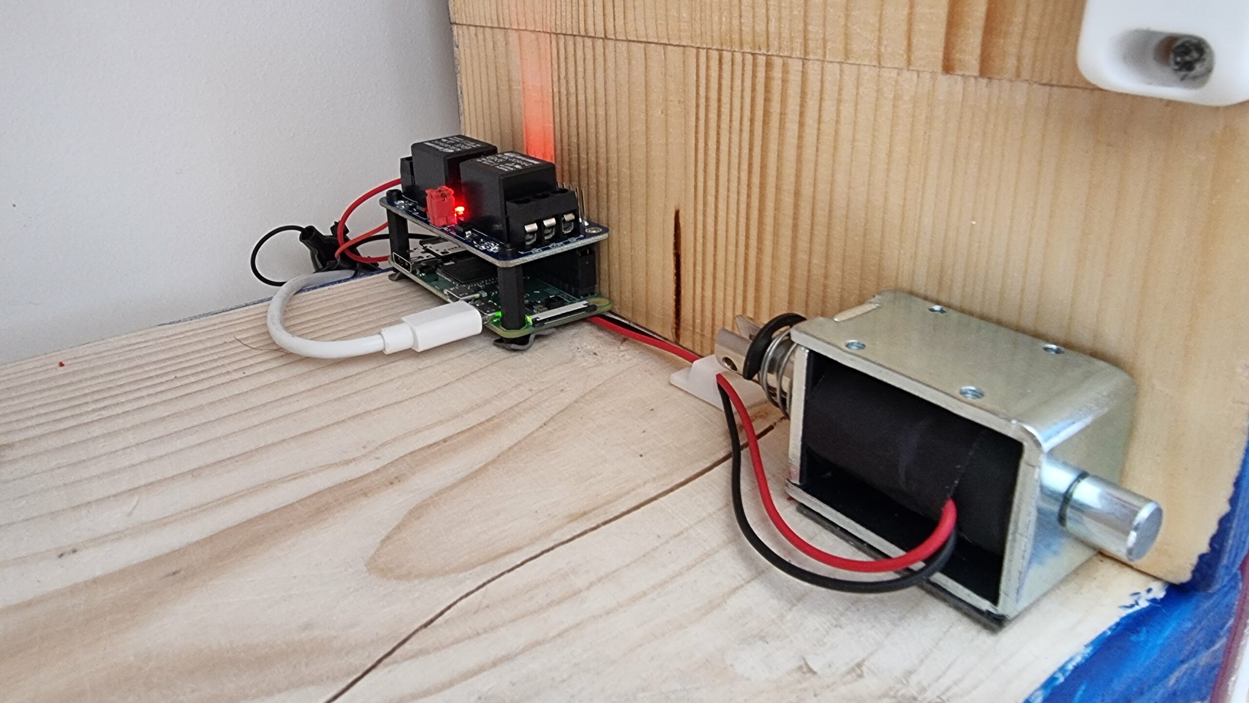 Full image of A Raspberry Pi Zero, relay, and solenoid assembly on the bottom outside edge of the inside of the cabinet.