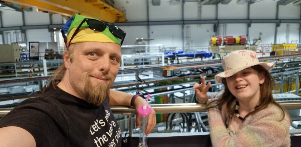 Dan with a child in front of beamlines coming out of the Diamond Light Synchrotron ring.