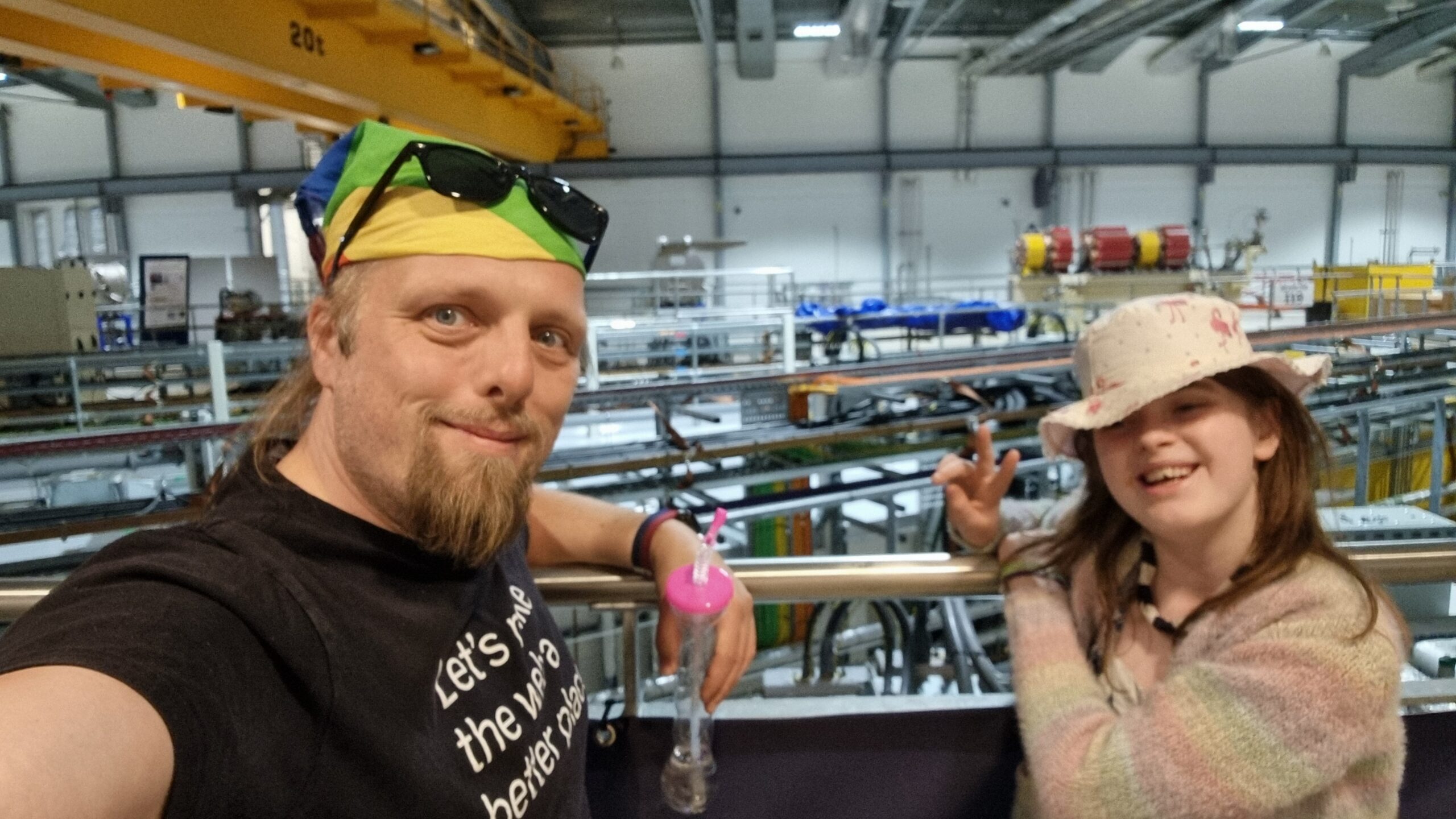 Full image of Dan with a child in front of beamlines coming out of the Diamond Light Synchrotron ring.