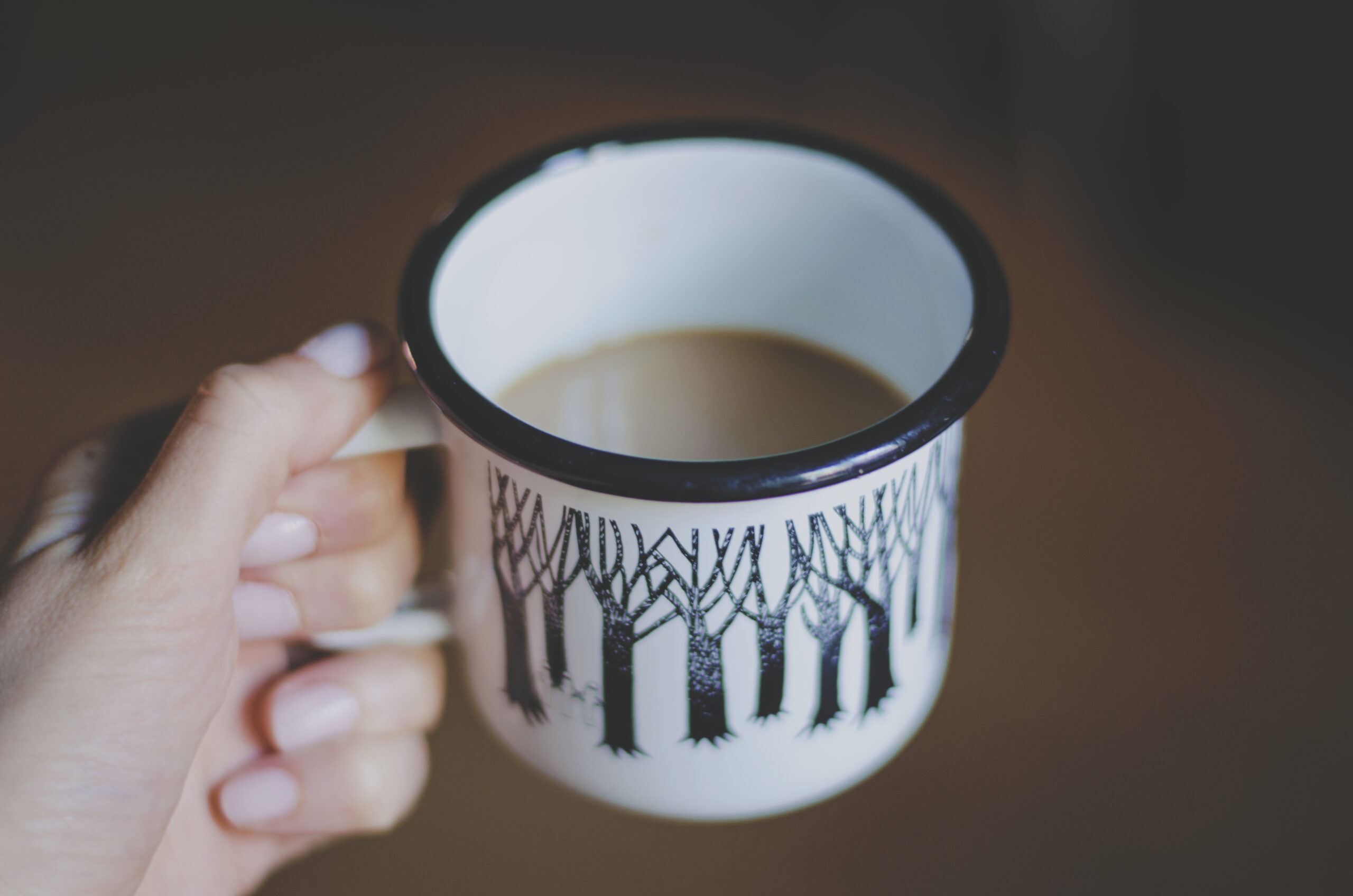 Full image of A mug of tea held by the handle.