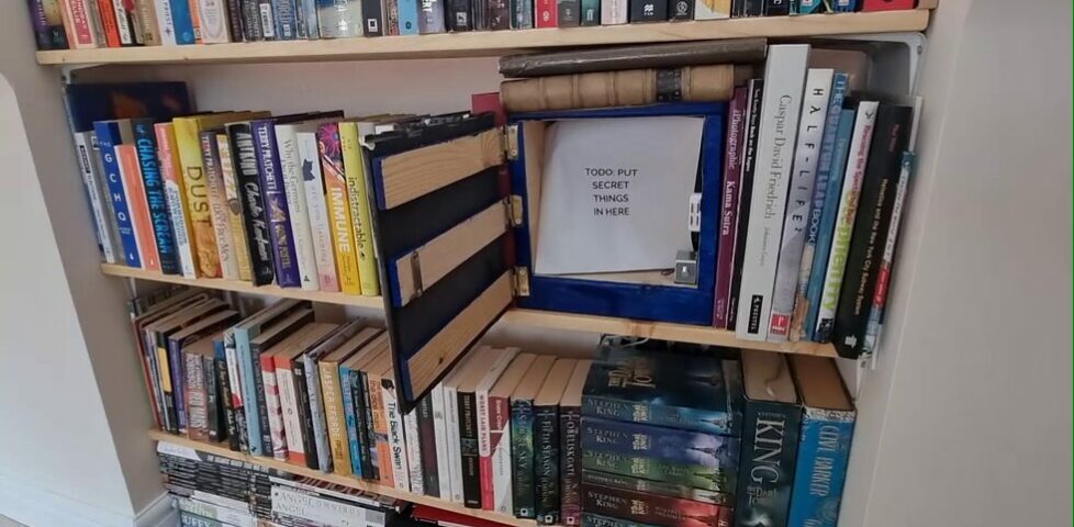 A bookshelf cabinet, open, containing a note that reads: 'TODO: PUT SECRET THINGS IN HERE'.
