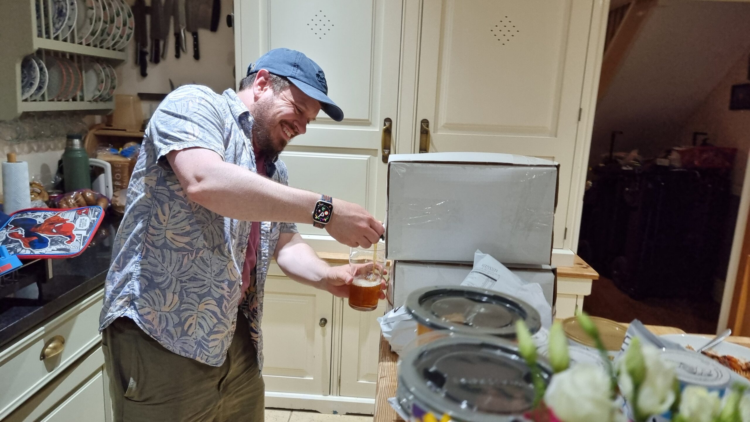 Full image of A man wearing a cap pours himself a beer from a 10-litre box.