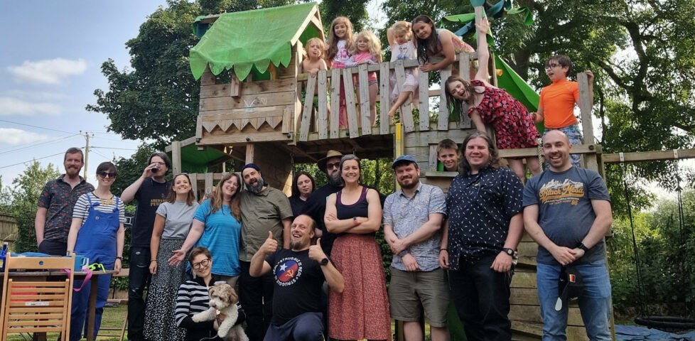 14 adults, 8 children, and a dog stand on/in front of a garden climbing frame: Dan is in the centre.