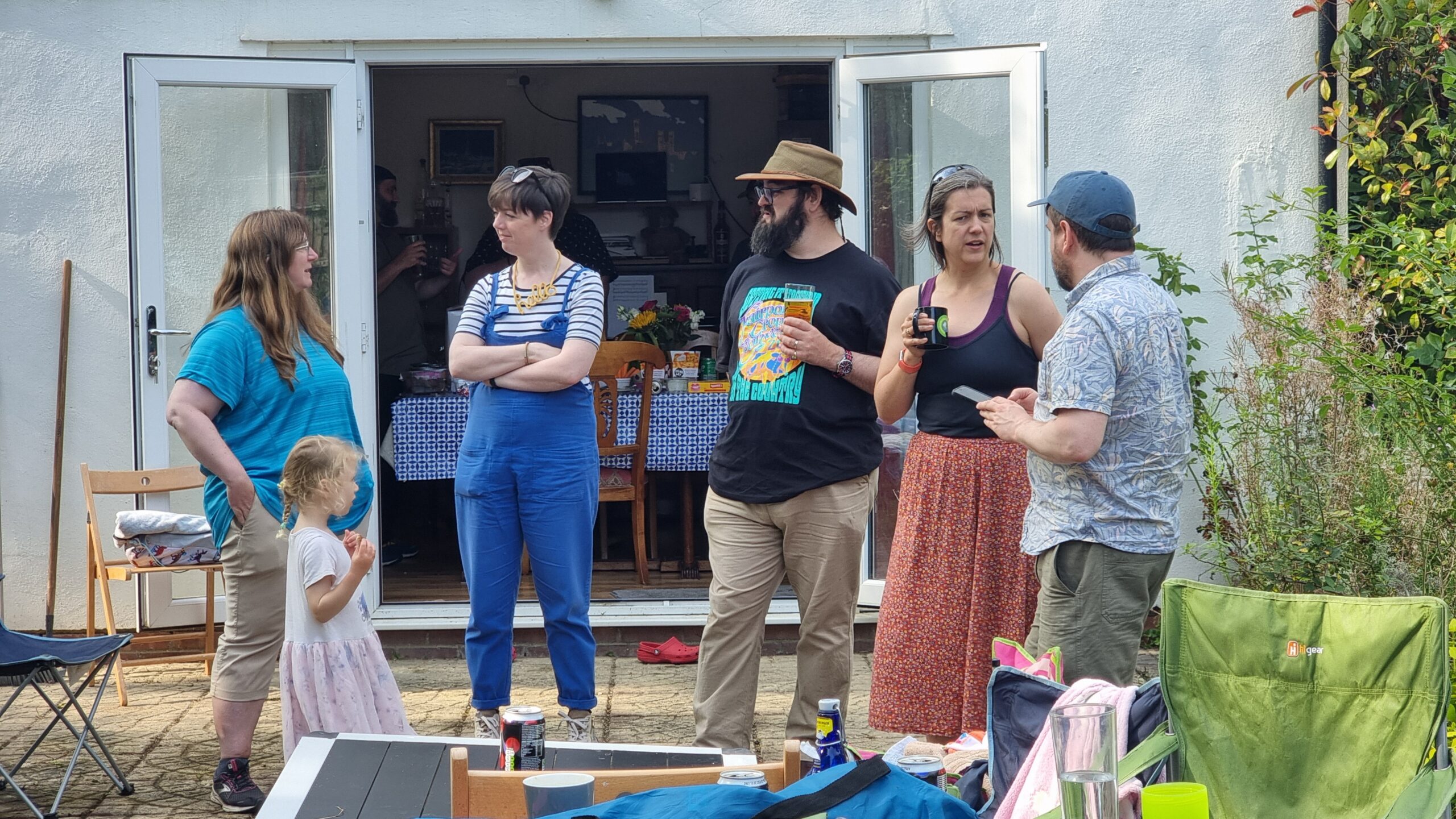 Full image of A group of adults stand around on a patio, socialising.