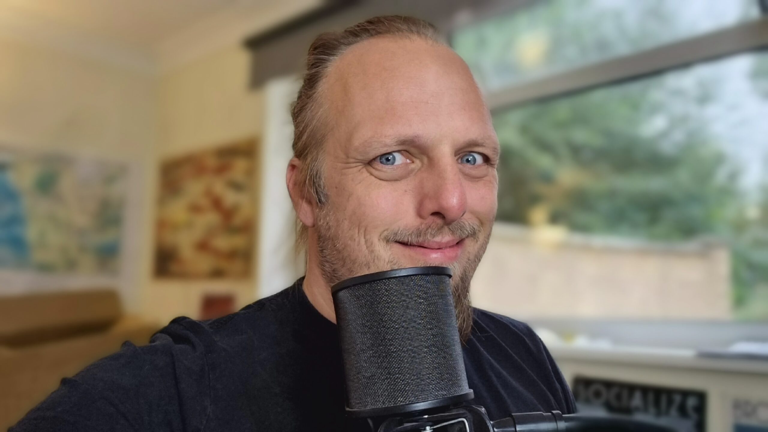 Full image of Dan, a microphone in front of him, smiles at the camera.