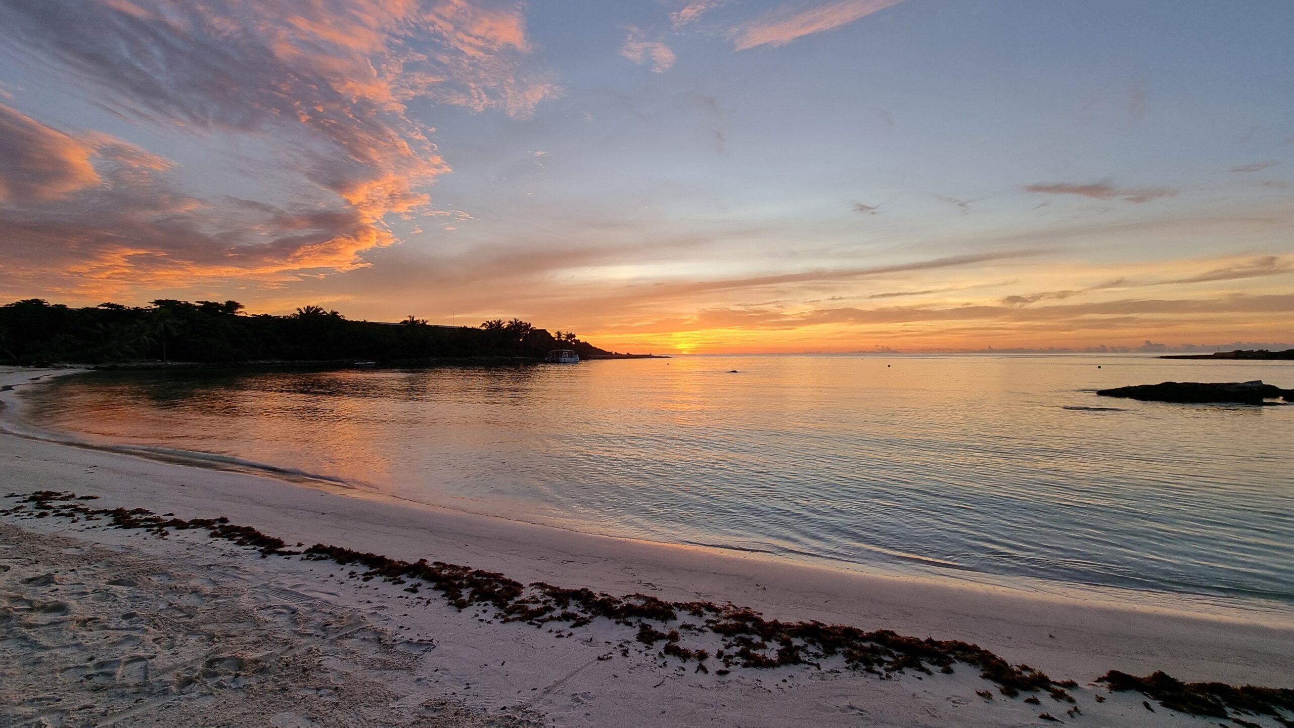 Full image of Sun rising over the sea as seen from a tropical beach.