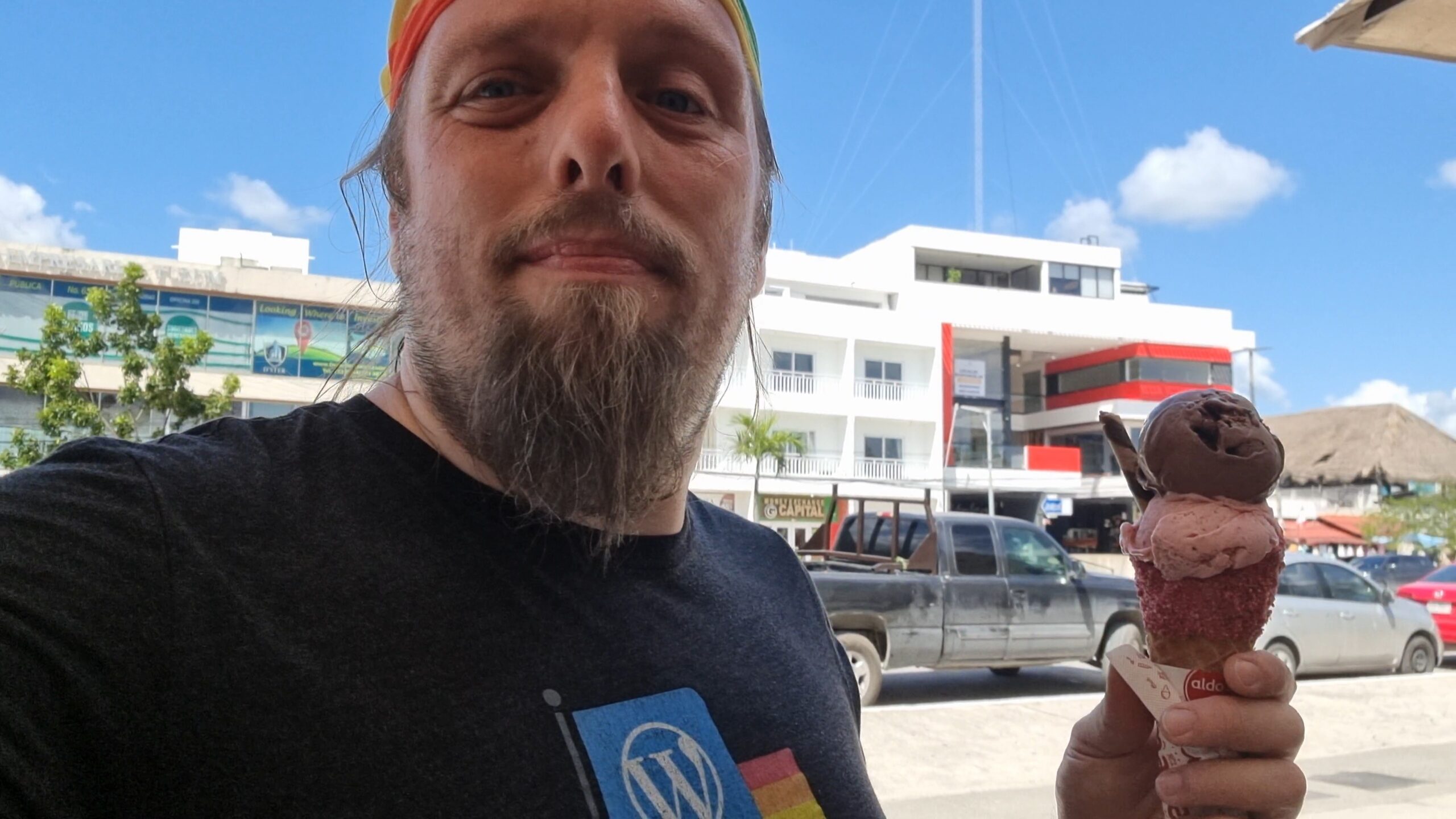 Full image of Dan, wearing a rainbow bandana, with an ornate ice cream cornet in a Mexican city.