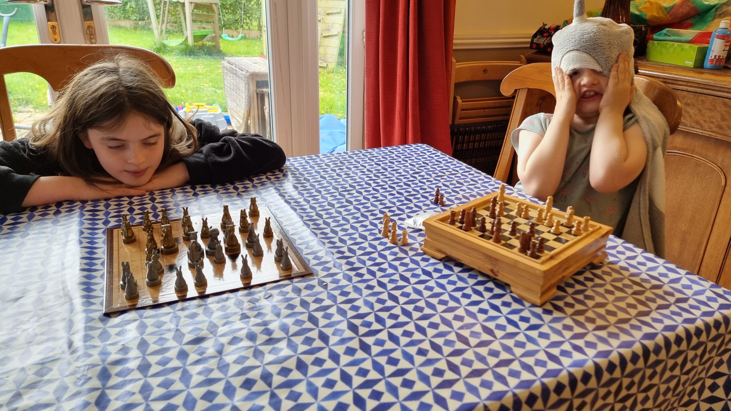 Full image of Two frustrated-looking children each sit in front of a separate chessboard (the photographer is presumably playing both of them).