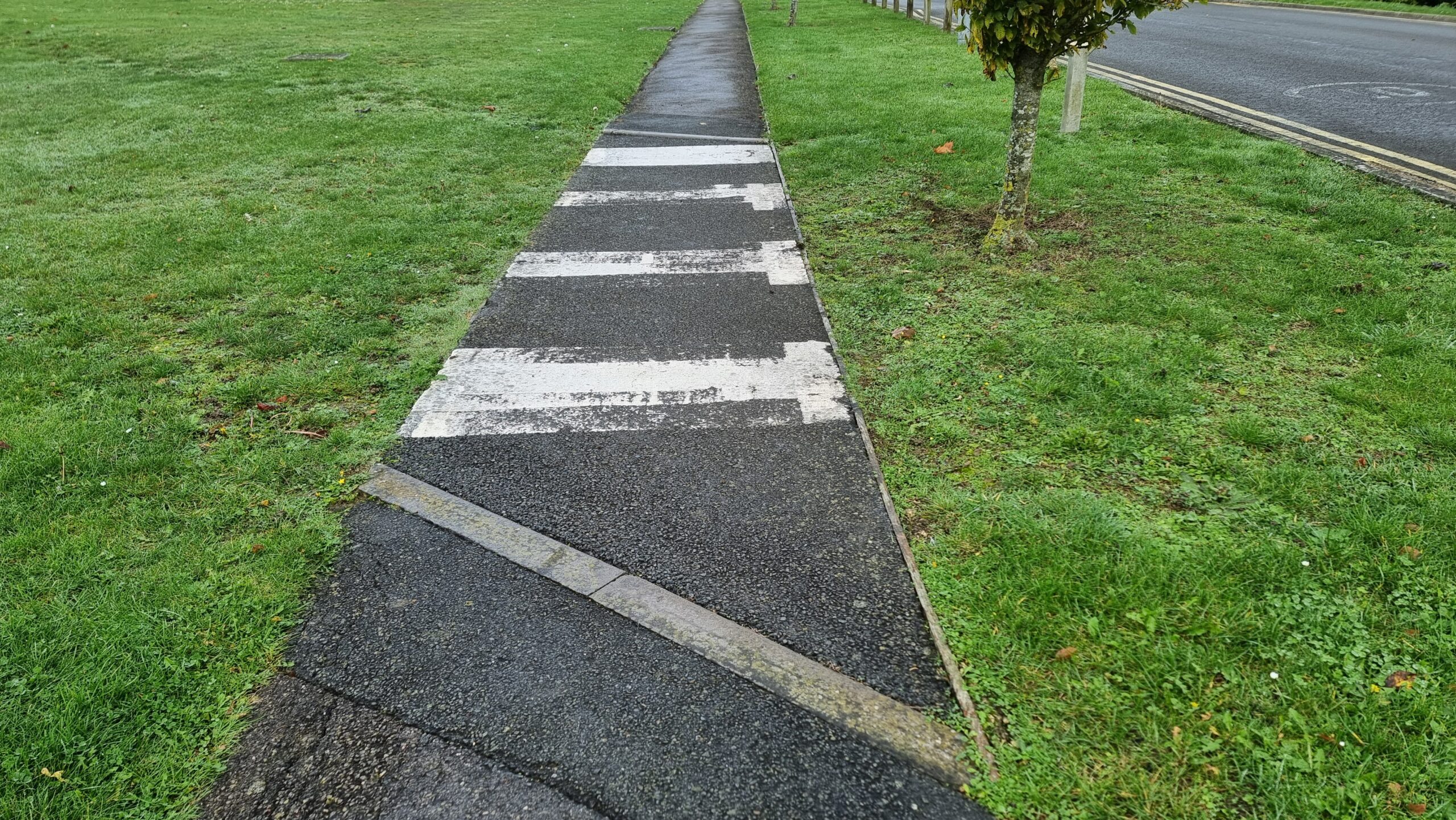Full image of A footpath becomes a zebra crossing despite there being no road to cross, just a lawn (probably there USED to be a road).