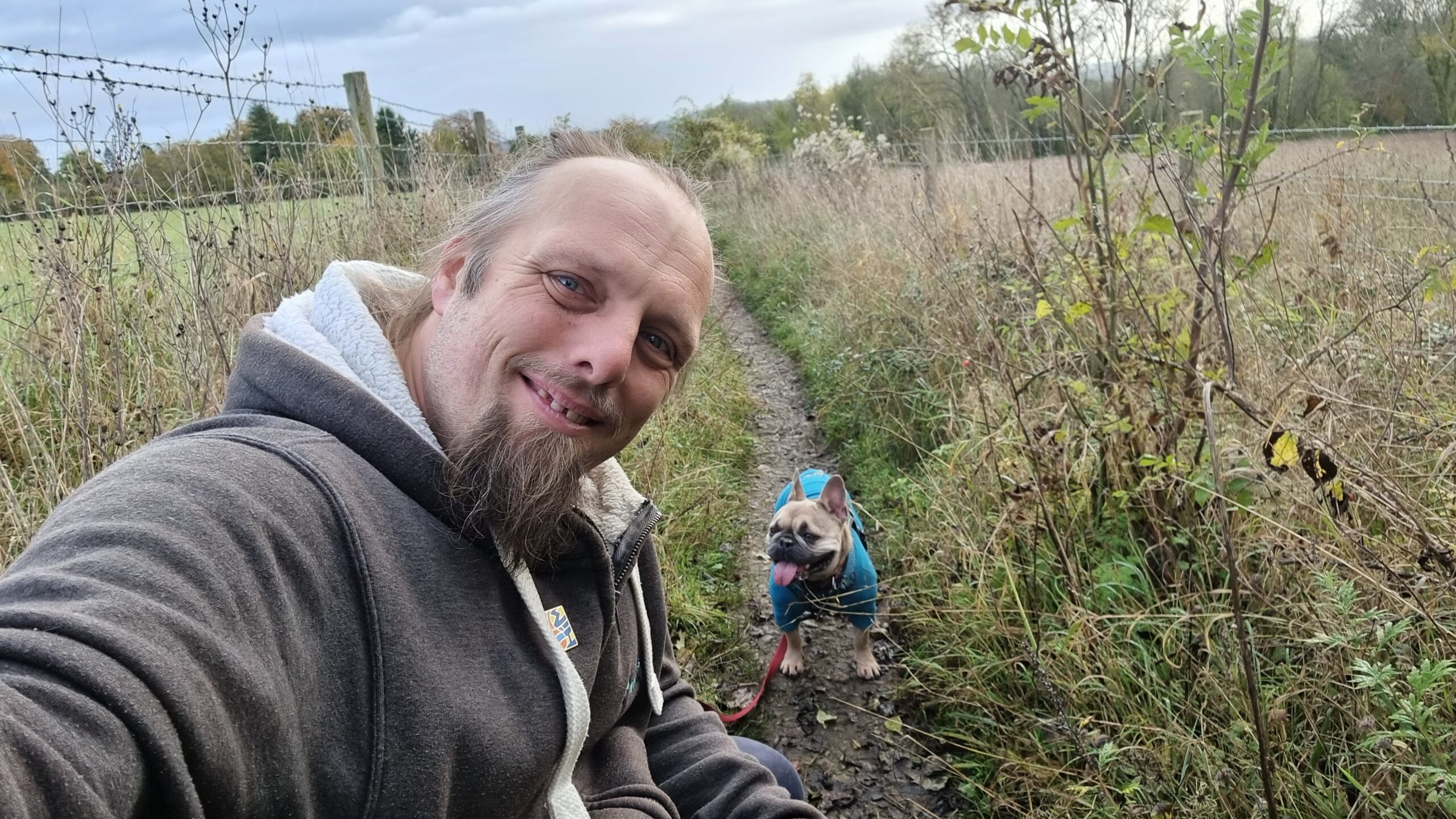 Full image of Dan crouches by his dog to take a selfie.