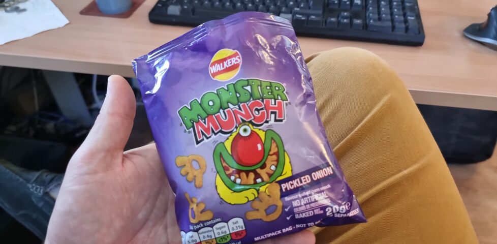 A packet of Pickled Onion Monster Munch, held in a hand.