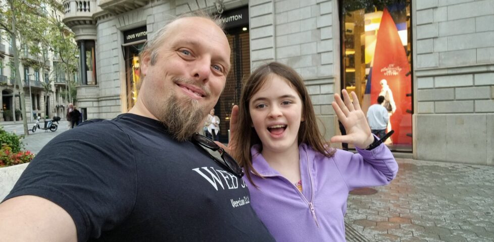 Dan and a child wave in a street.