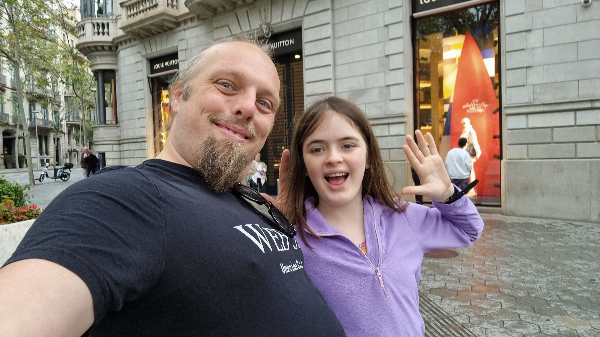Full image of Dan and a child wave in a street.