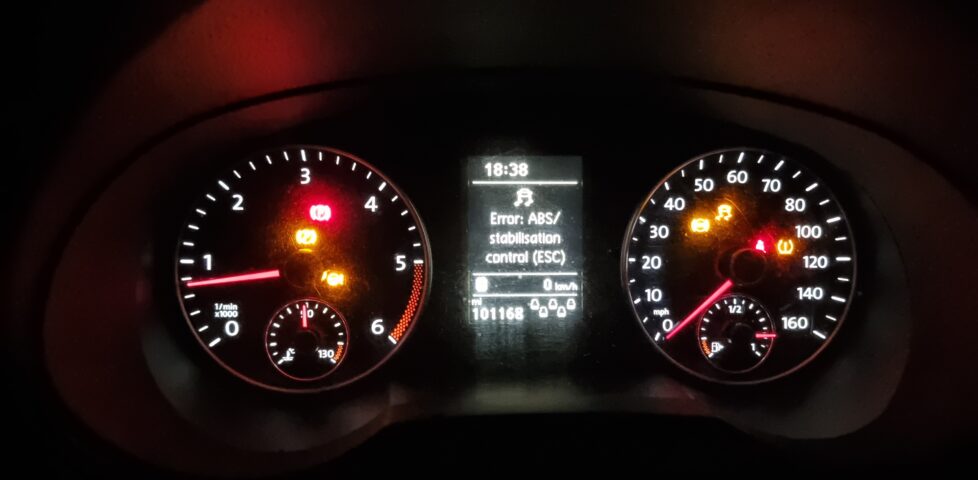 Car dashboard with seven different warning lights on, plus a message advising that ABS and ESC are not working.