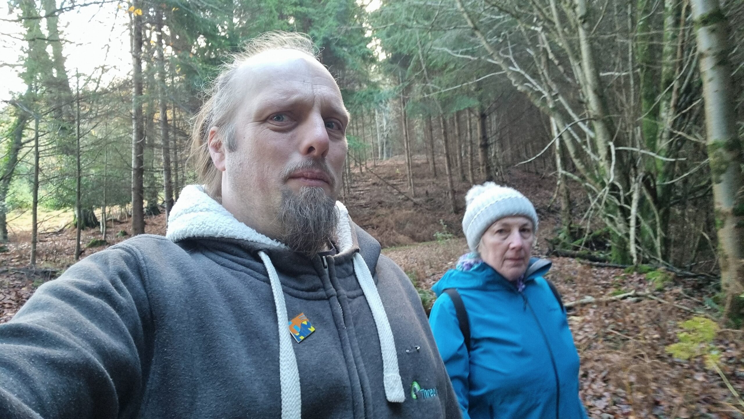 Full image of Dan looks concerned next to his mother, in a forest.