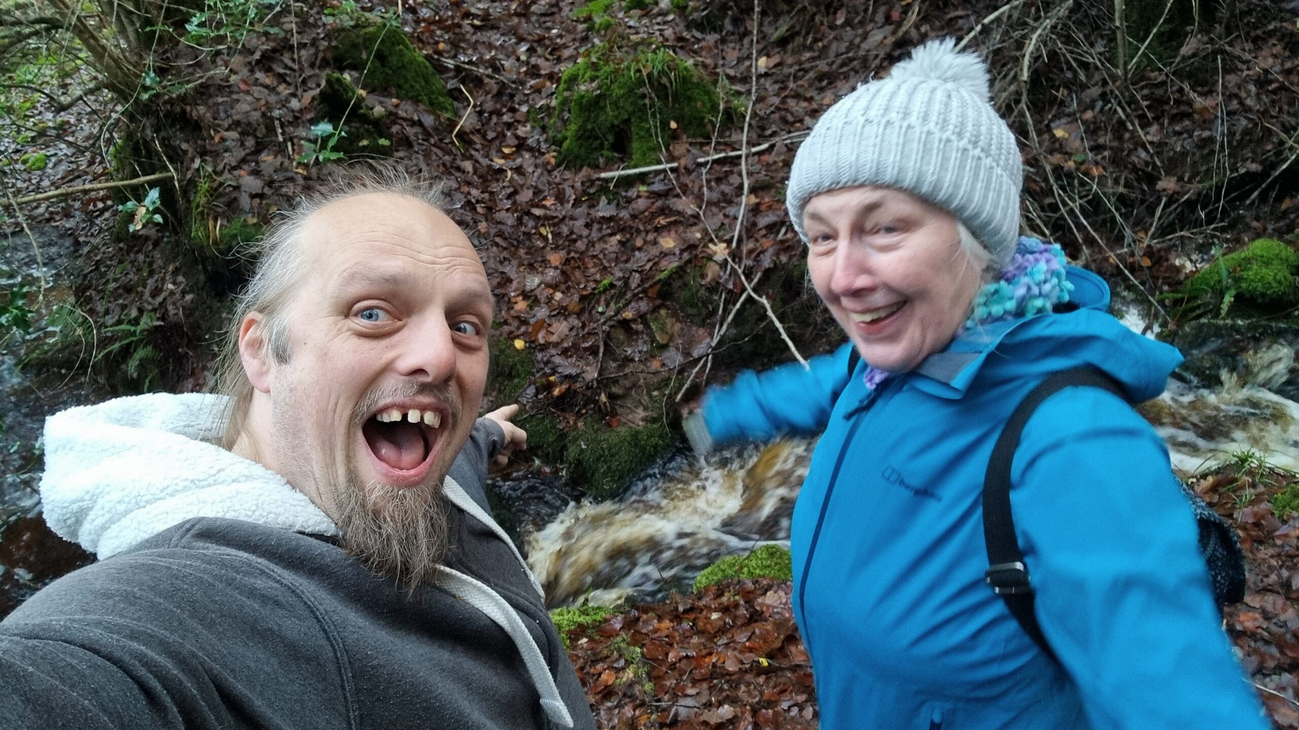 Full image of Dan and his mother cheer alongside a raging stream.