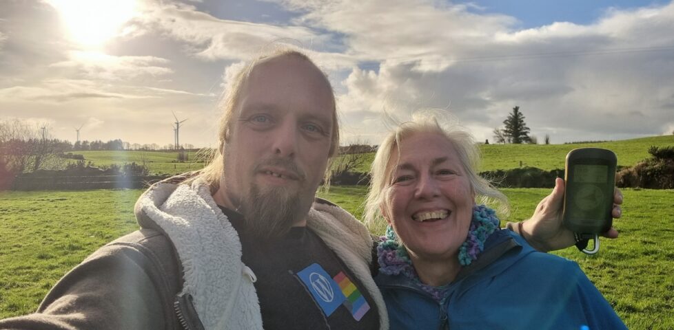 Dan and his mother grin in a grassy field.