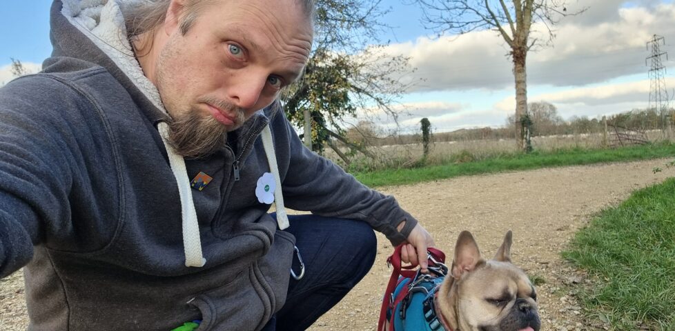 Dan and his dog on a footpath with a field in the background.