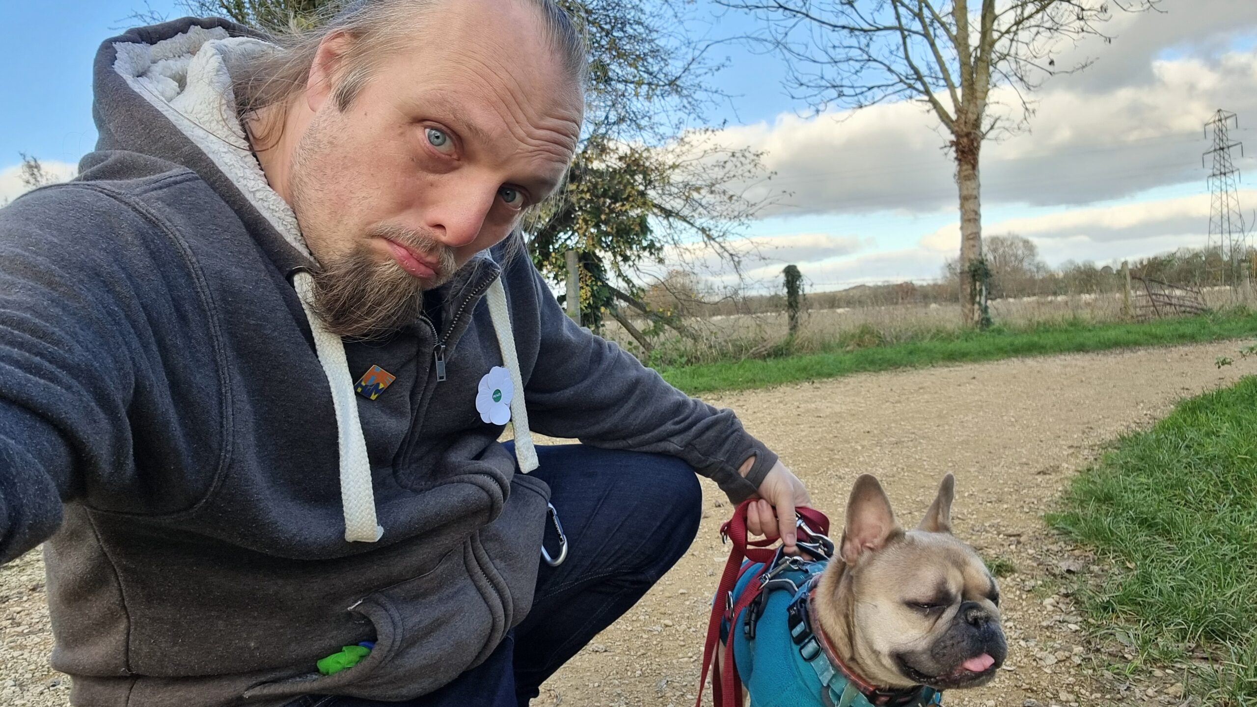 Full image of Dan and his dog on a footpath with a field in the background.