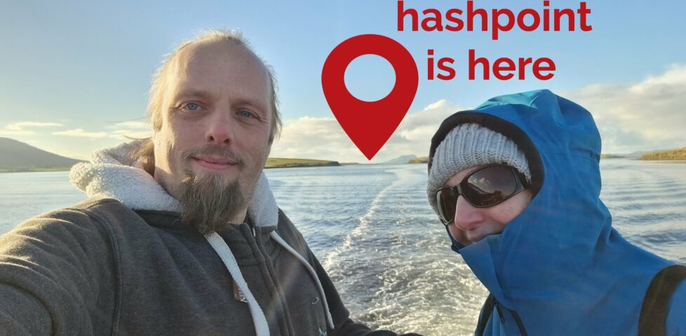 Dan and his mother ride on the back of a boat through a bay full of islands. In the distance, the distinctive shape of Clare Island can be seen, jutting out from the sea, and to the left of it a red pin is superimposed upon the image with the message 'hashpoint is here'.
